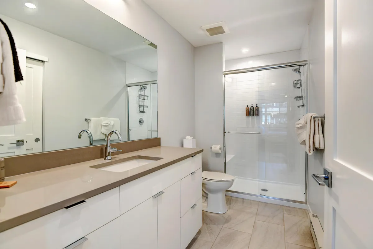 A bright and fresh bathroom featuring a vanity with a large sink, a spacious mirror, and a walk-in shower area. The clean lines and inviting vibe encourage relaxation and self-care, ideal for unwinding after adventurous days.